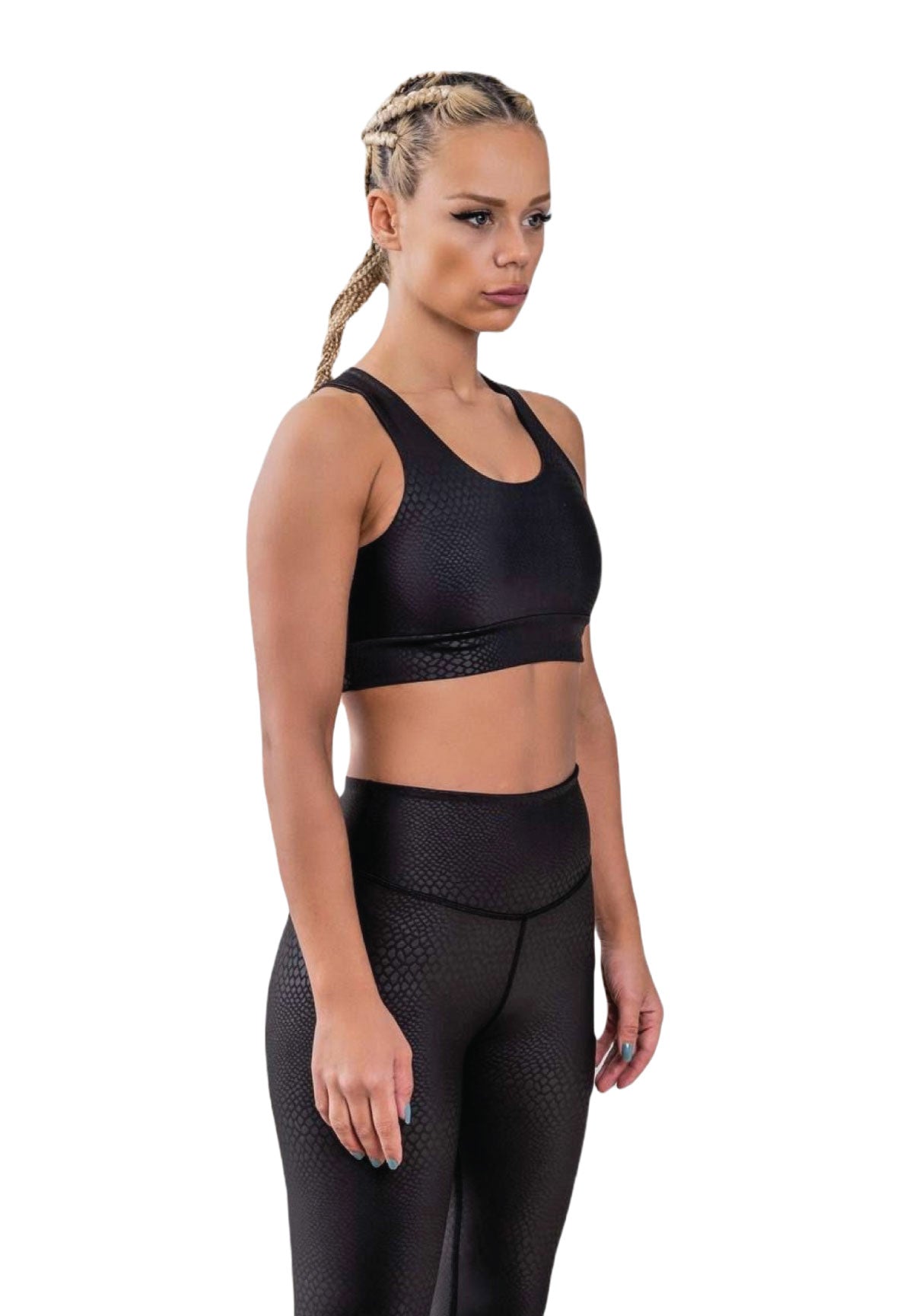 Person mit geflochtenen Haaren in Lisminas 937 Leder-Look-Leggings in Schwarz Snake und einem schwarzen Sportoutfit.